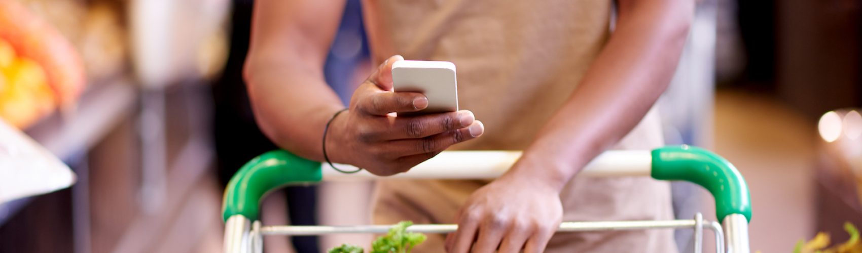 Closeup shot of an unidentifiable man using a cellphone while shopping in a grocery store